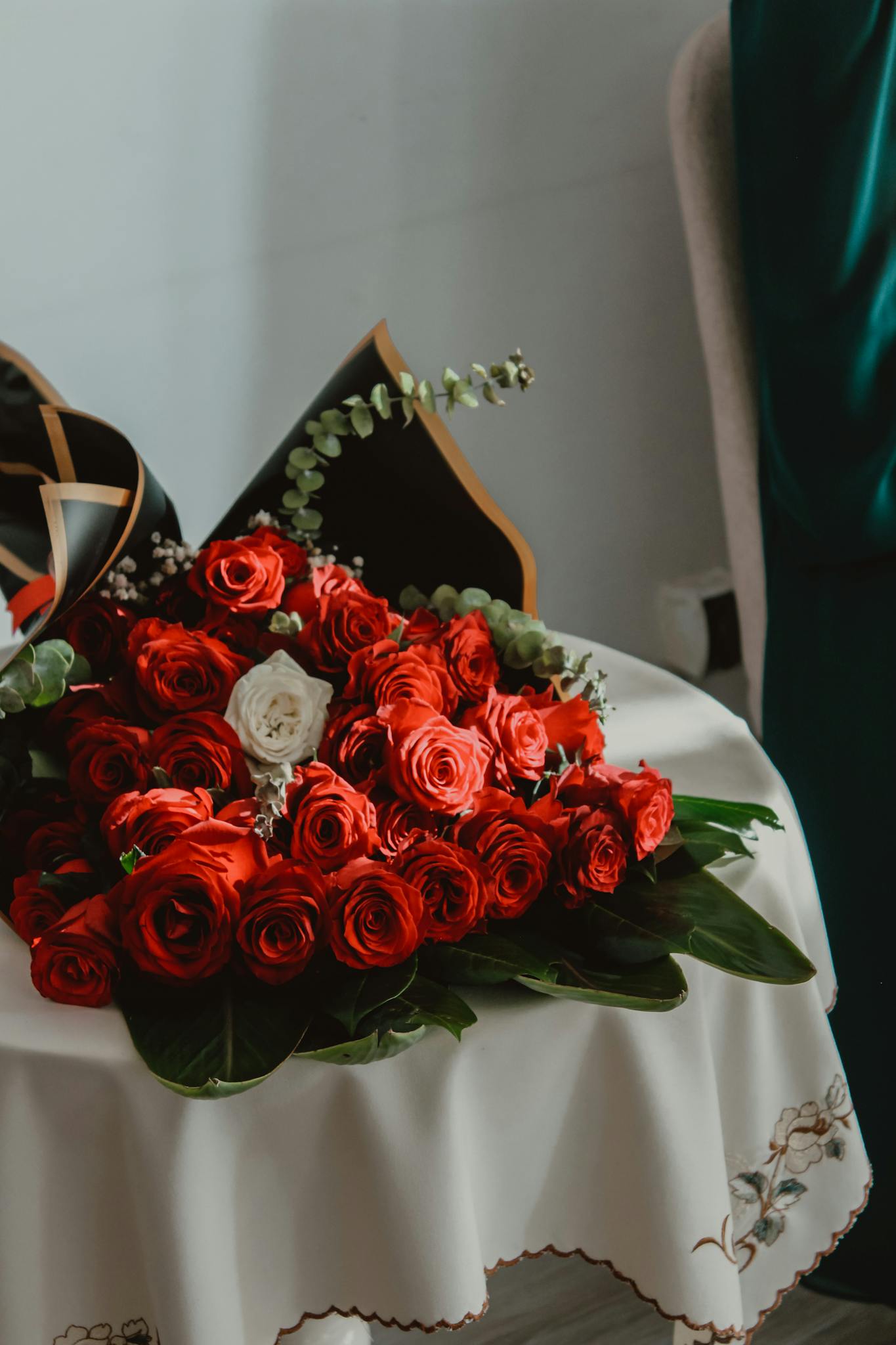 Beautiful arrangement of red roses with a single white rose on a decorated table.